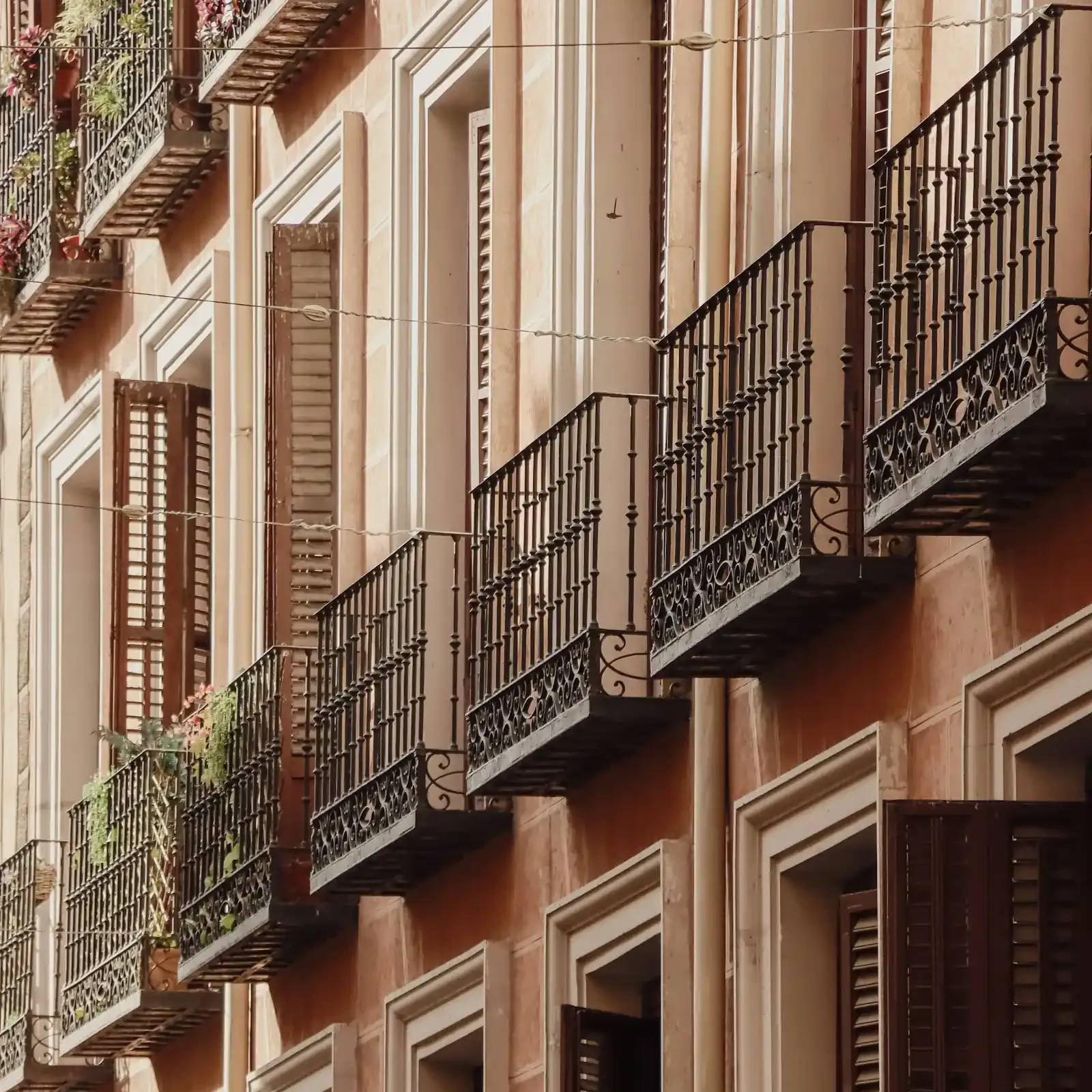 Fachada residencial madrileña con balcones de hierro y contraventanas